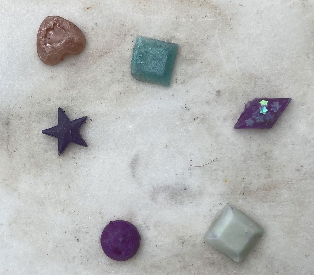 UV-resin test shapes on concrete: star, squares, and beads in colour.