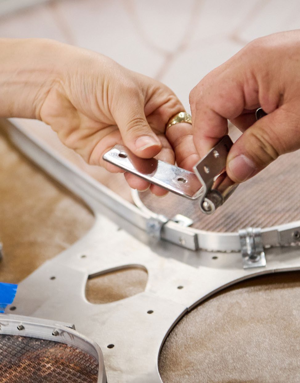 Hands fitting a metal bracket to an aluminum wing frame.